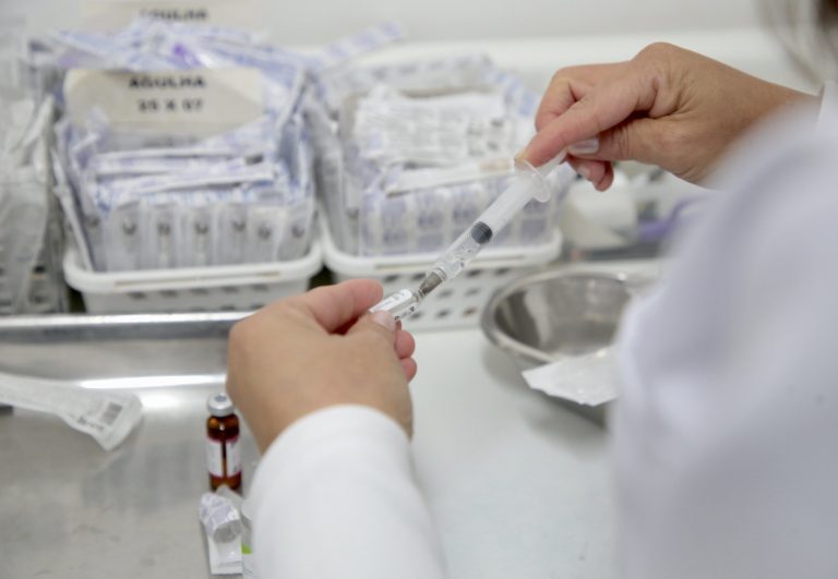 Enfermeira prepara vacina numa seringa