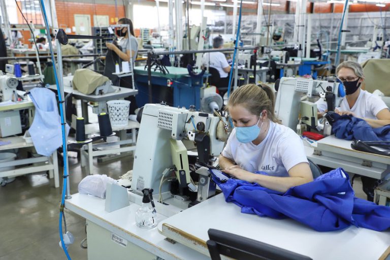 Mulheres trabalham costurando em indústria têxtil