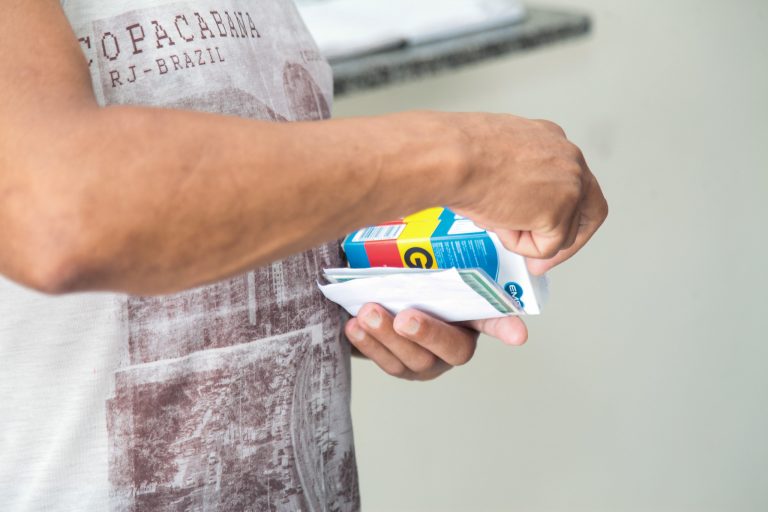 Uma pessoa segura algumas caixas de remédio e uma receita médica. A foto está cortada e não é possível ver o rosto da pessoa