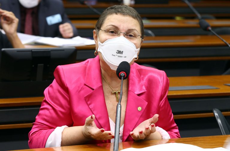 Deputada Tereza Nelma fala ao microfone. Ela usa um blazer rosa e uma máscara branca