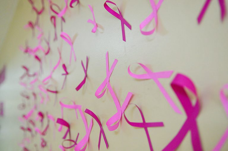 Laços rosas numa parede branca simbolizando a campanha contra o câncer de mama