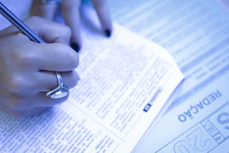 Foto de uma aluna com uma caneta marcando as respostas numa prova