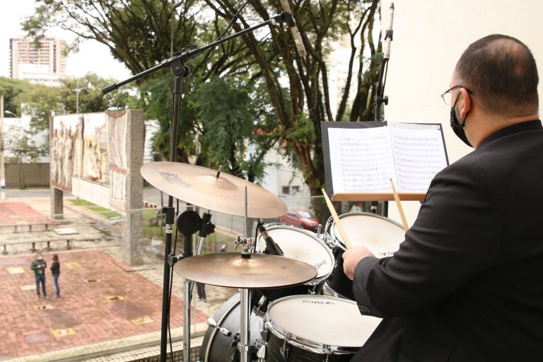 Um homem de costas toca bateria