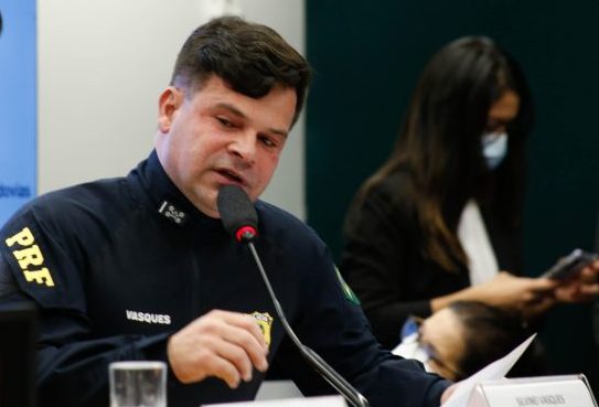 Um homem branco usa um uniforme preto com a sigla PRF em amarelo