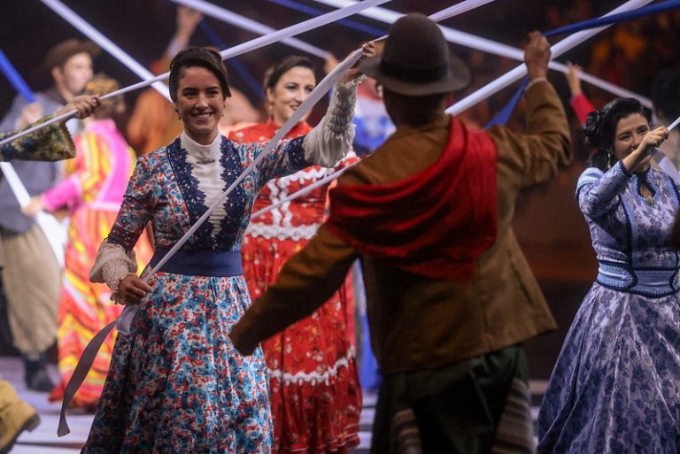 Cultura - dança - dança gaúcha - A dança do pau de fitas consiste em uma dança de roda, usando um mastro enfeitado de aproximadamente três metros e longas fitas coloridas amarradas no topo